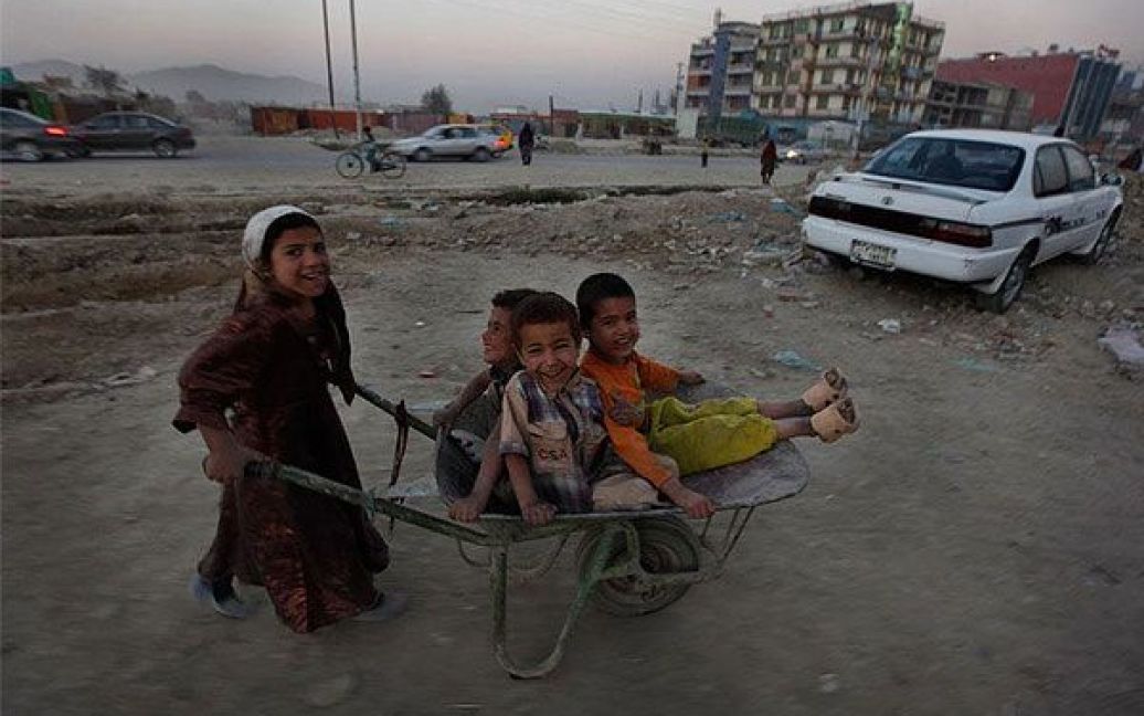 Афганістан, Кабул. Афганська дівчинка штовхає возик з трьома хлопцями у передмісті Кабула. / © bigpicture.ru