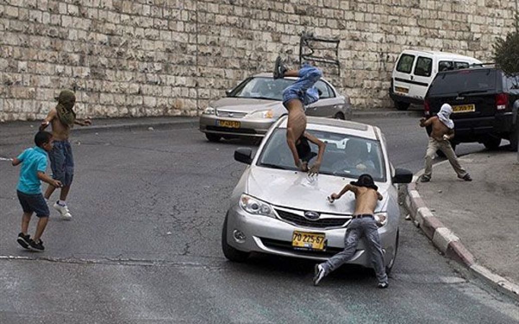 Єрусалим. Ізраїльський водій збиває палестинських підлітків, одягнених у маски, які стояли серед групи молодиків, що кидали каміння в ізраїльські автомобілі у арабському районі Єрусалиму Сільван. / © AFP