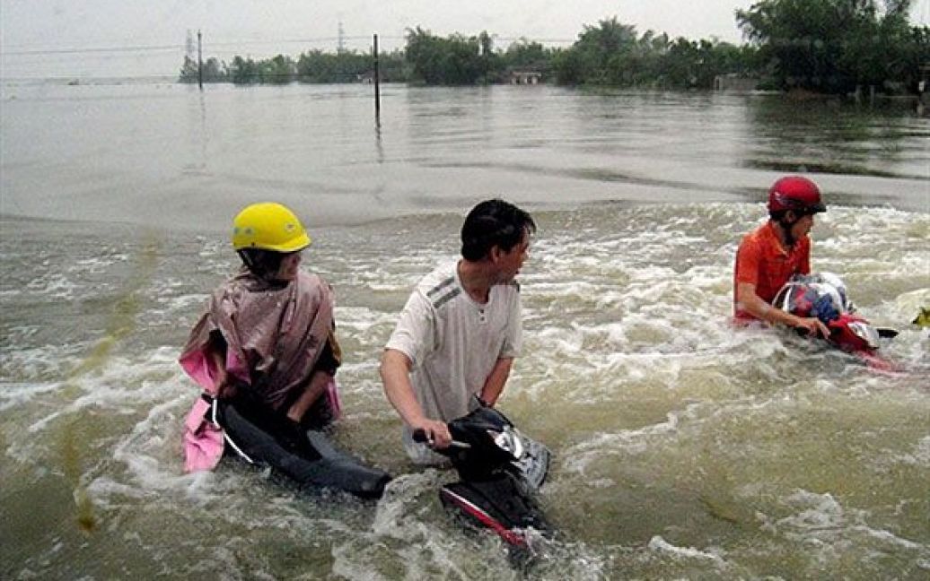 В&#039;єтнам, Хатінь. Люди ведуть свої мотоцикли затопленим національним шосе номер один у районі Кам Суен, провінція Хатінь. В результаті повеней у В&rsquo;єтнамі, загинули щонайменше 23 людини, близько 116 тисяч людей були евакуйовані зі своїх будинків. / © AFP