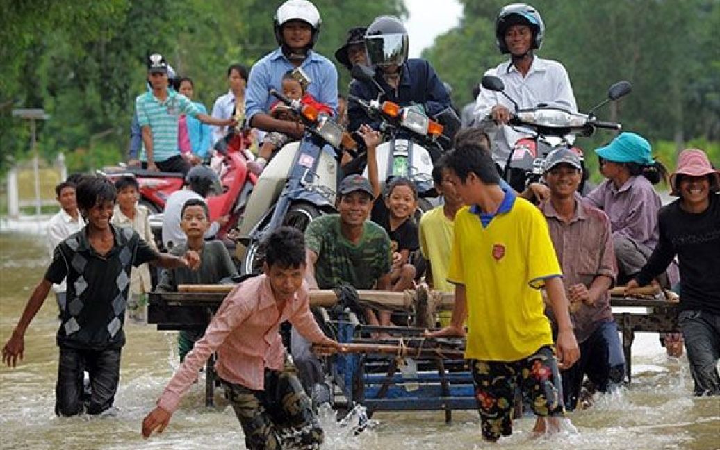 Камбоджа, Такео. Камбоджійські робочі штовхають платформу, завантажену людьми і мотоциклами, через затоплену вулицю у провінції Такео. Сильні повені, від яких потерпають багато провінцій Камбоджі, охопили країну після двох днів сильних дощів. / © AFP