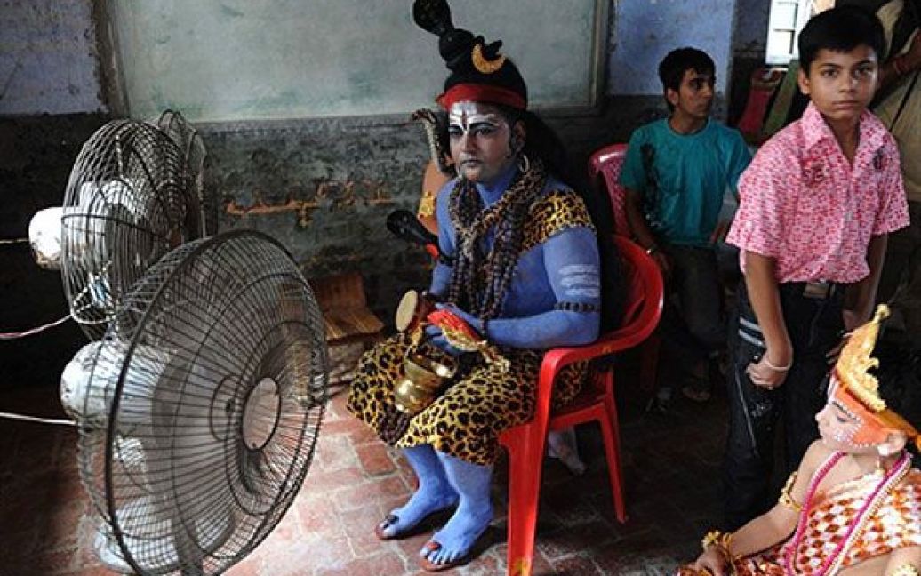 Індія, Амрітсар. Індійський чоловік у костюмі індуїстського бога Шиви, пофарбований у синій колір, чекає на участь в урочистій процесії напередодні свята "Джанмаштамі", дня народження бога Крішни. Згідно індійській міфології і священній книзі індуїзму "Пуранах", Крішна є втіленням бога Вішну, який втілився, щоб убити свого дядька по материнській лінії, злого короля Канза, і звільнити народ Матхура від його жорстокості. / © AFP