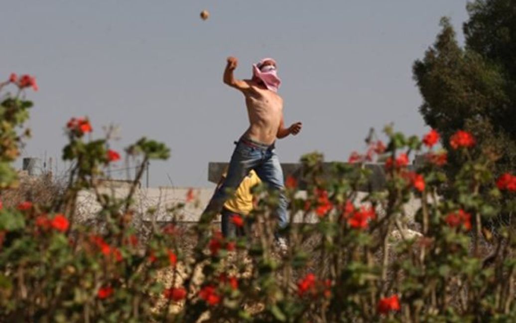 Молодий палестинець жбурляє кидає каміння у під час щотижневої демонстрації проти окупації Ізраїлем територій Західному Березі Йордану. / © AFP