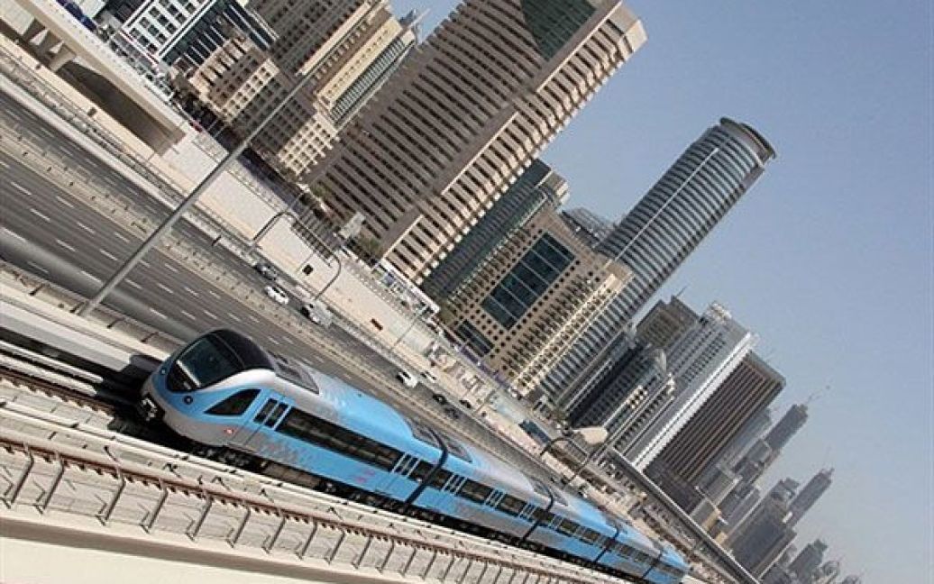 Об&#039;єднані Арабські Емірати, Дубаї. Дубайський швидкісний потяг метро їде повз трасу Шейха Заєда у Дубаї. Побудоване у місті швидкісне метро сильно змінило транспортну "картину" у Дубаї, чиї мешканці полюбляють їздити всюди на автомобілях. Але все ще, через рік після того, як перший поїзд метро вирушив у дорогу, метро бореться за пасажирів. / © AFP