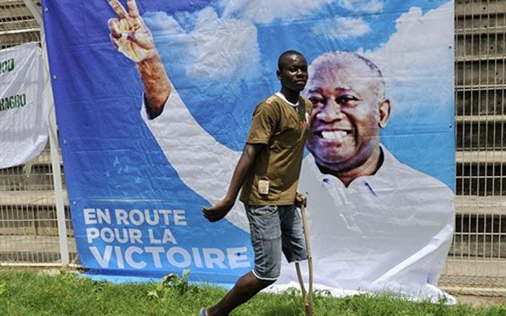 Кот д&rsquo;Івуар, Буаке. Чоловік на милицях проходить повз плакат президента Кот-д&#039;Івуару Лорана Гбагбо під час мітингу на стадіоні в Буаке напередодні президентських виборів, які мають відбутися 31 жовтня 2010 року. / © AFP