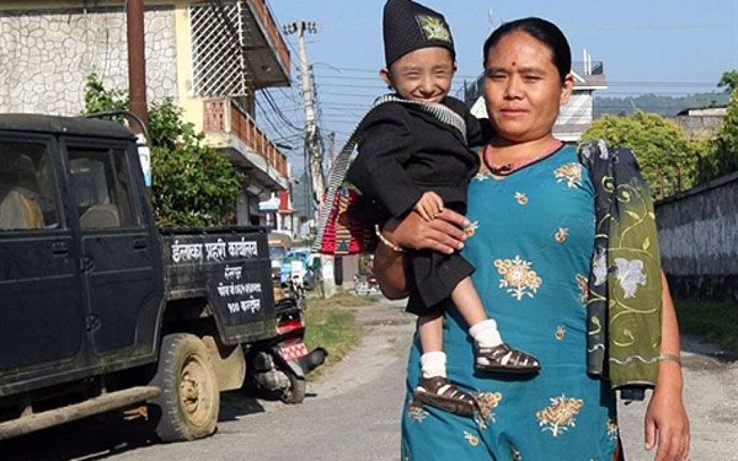 Мати з сином йде вулицею селища Похара / © AFP