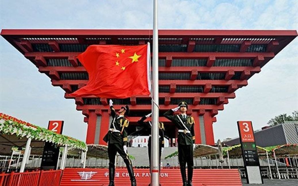 Китай, Шанхай. Китайські солдати урочисто розгортають національний прапор Китаю перед китайським павільйоном на всесвітній виставці "World Expo 2010" у Шанхаї. / © AFP