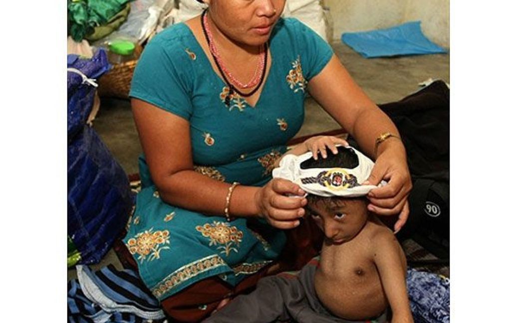 Мати Магара Дхана Майя Тапа допомагає йому вдягнутись / © AFP
