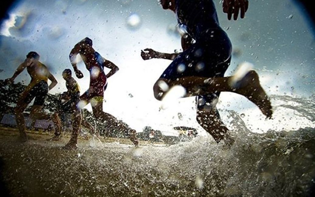 Учасники тріатлону серед чоловіків виходять з води після першого етапу змагань. / © AFP