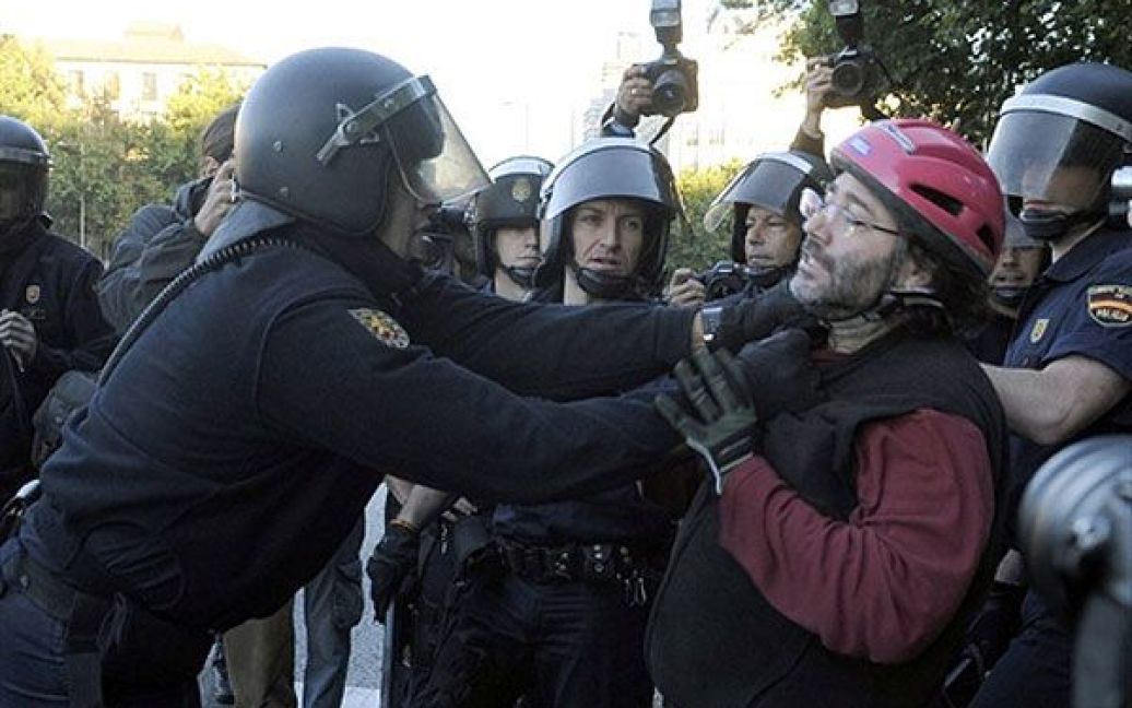 Іспанія, Мадрид. Поліцейський перед залізничною станцією Аточа атакує велосипедиста, який бере участь у загальнонаціональному страйку, який прокотився Іспанією. Профспілки обурені рішеннями політиків після того, як соціалістичний уряд Іспанії був змушений використати непопулярні заходи для "латання дір" у економіці країни. / © AFP
