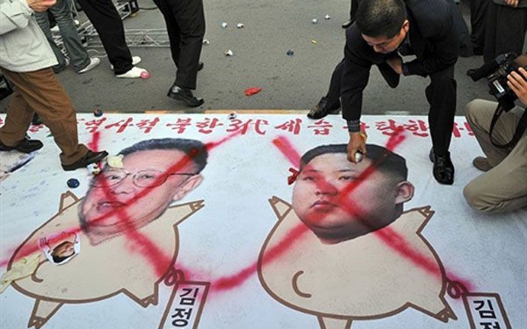 Республіка Корея, Сеул. Південнокорейські активісти малюють червоні хрести на карикатурах лідера Північної Кореї Кім Чен Іра та його молодшого сина Кім Чен Ина під час мітингу, на якому було засуджено "комуністичну династію", що вже три покоління керує Північною Кореєю. Північна Корея офіційно назвала Кім Чен Ина наступним лідером, який займе місце свого хворого батька. / © AFP