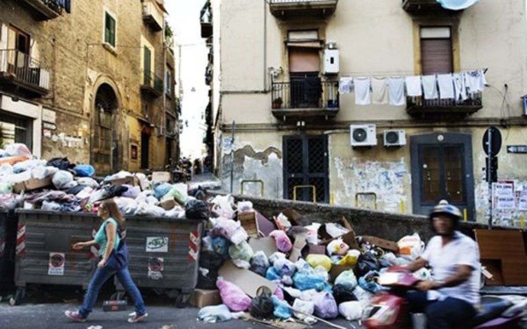 Люди проходять повз сміття на вулицях Неаполі. Учора акція протесту проти будівництва сміттєзвалища на схилах Везувію закінчилися сутичкою демонстрантів із поліцією та підпалом двох сміттєвозів. / © AFP