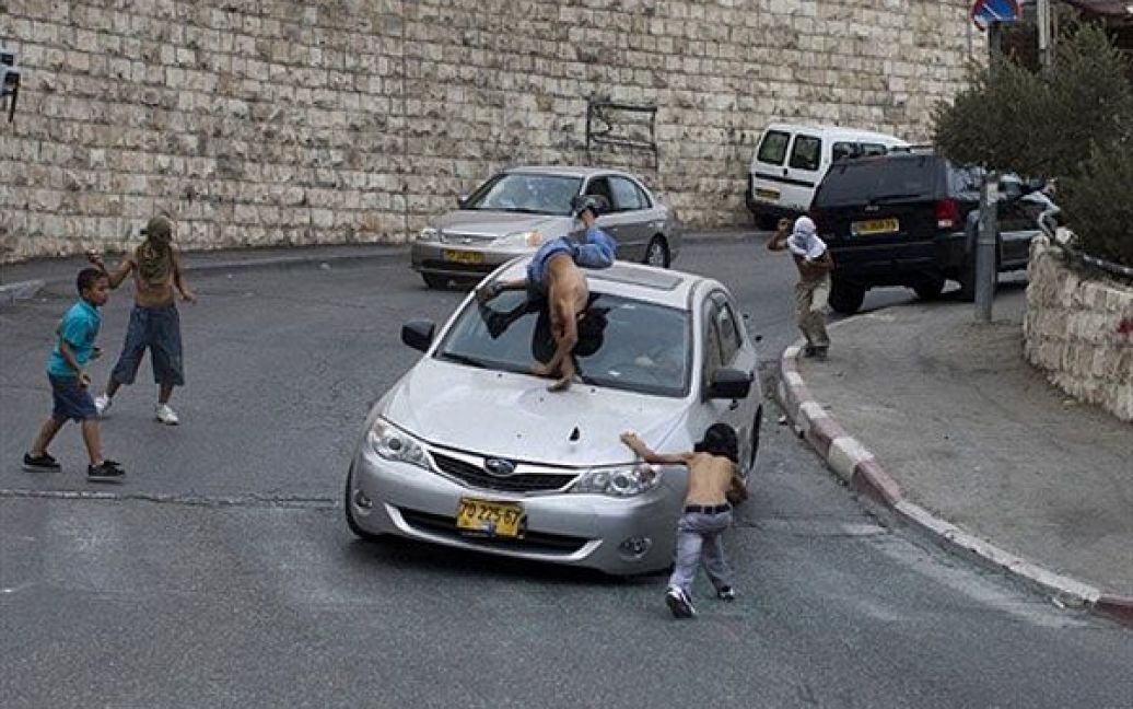 Ізраїльський водій збиває палестинського юнака, який стояв посеред групи молодих людей, що почали кидати каміння у ізраїльські автомобілі в арабському районі Єрусалиму Сільван / © AFP