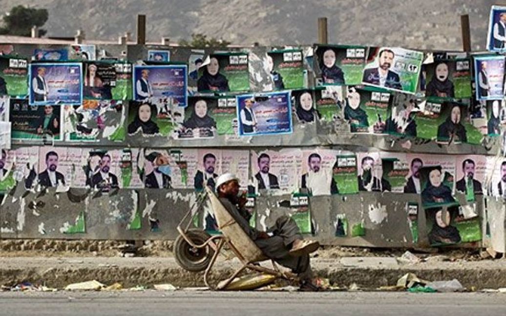 Афганістан, Кабул. Афганський робочий лежить на тачці перед стіною, заклеєною плакатами кандидатів у депутати на загальних виборах. Талібан пригрозив атакувати виборчі дільниці під час парламентських виборів у Афганістані, а збройні сили НАТО і афганські війська розгорнули масові операції із забезпечення безпеки під час голосування. / © AFP