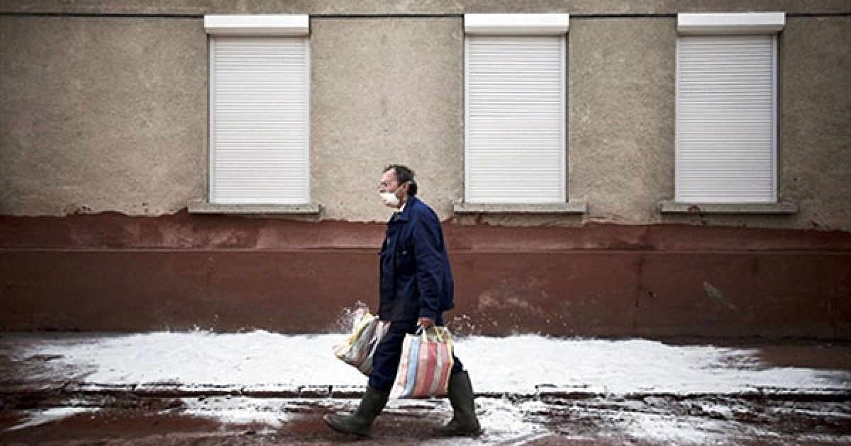 Угорщина, Девечер. Місцевий житель у захисній масці йде вулицею, засипаною гіпсом, після того, як у місті стався вилив токсичного червоного шламу. Угорська влада заявила, що загроза другого виливу хімічної речовини була відвернена і мешканці зможуть повернутися додому. / © AFP