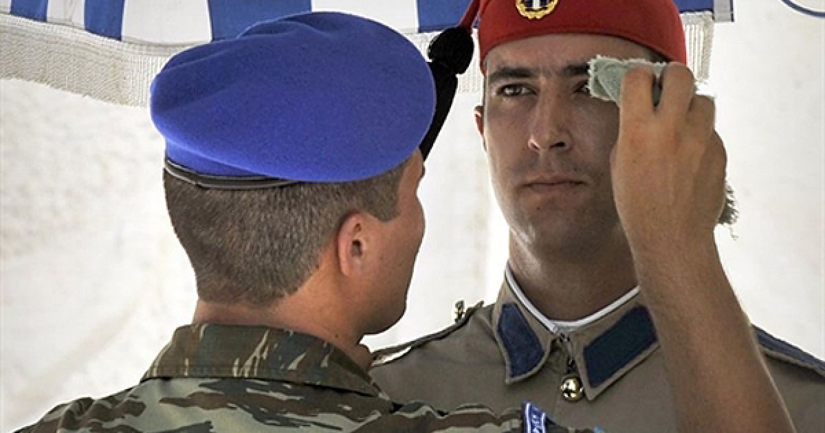 Солдат почесної варти на могилі невідомого солдата у Афінах витирає своєму напарникові піт на чолі. Температура повітря у Афінах сягнула 40 градусів Цельсія. / © AFP