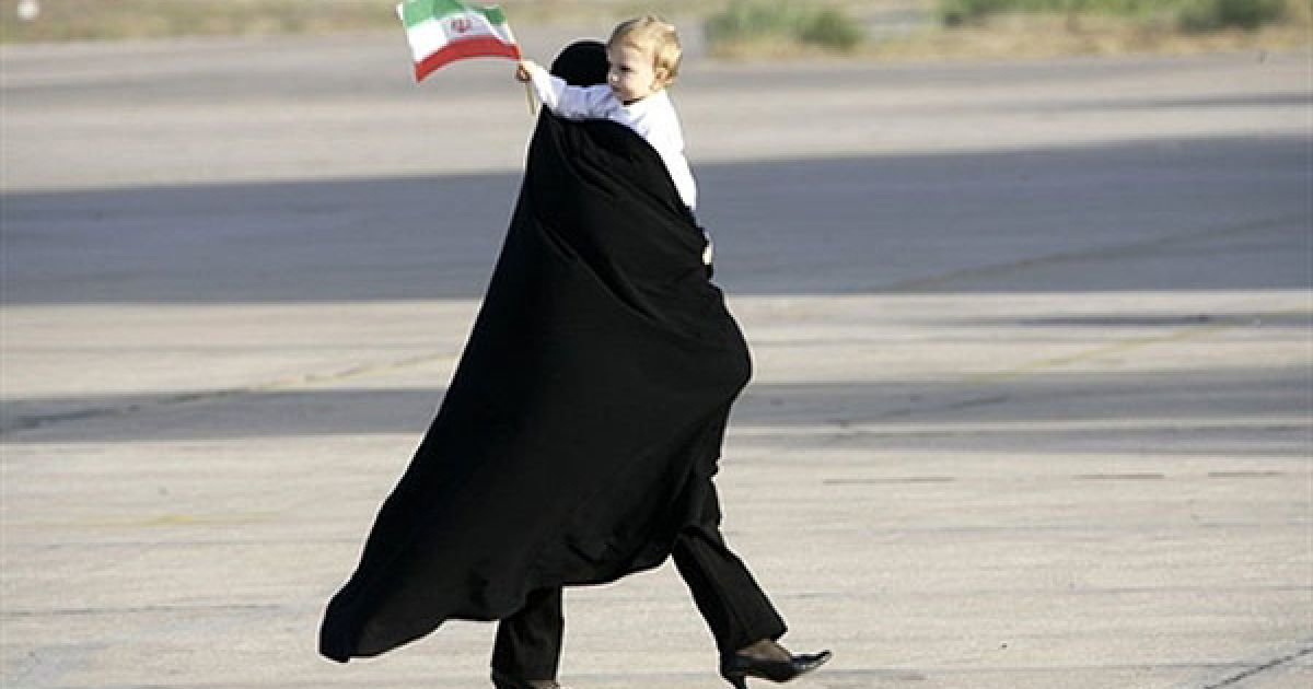 Ліван, Бейрут. Іранська жінка несе на руках дитину, що тримає в руці прапорець, доки вона чекає на прибуття до міжнародного аеропорту Бейрута президента Ірану Махмуда Ахмадінежада. Махмуд Ахмадінежад здійснює свій перший візит на схід Лівану. Кульмінацією дводенного візиту Ахмадінежада має стати відвідання лівано-ізраїльського кордону. / © AFP