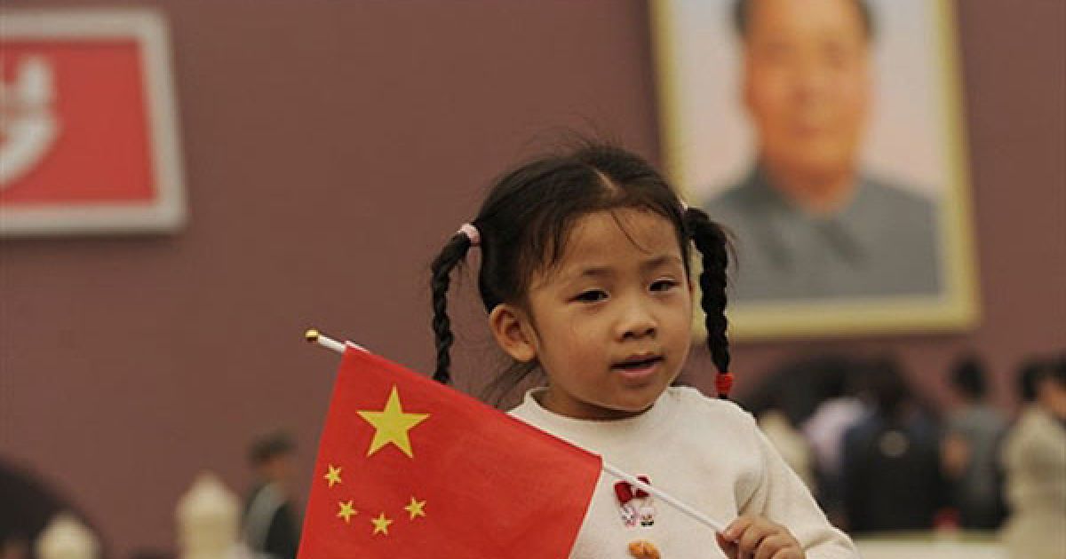 Пекін, Китай. Молода дівчинка тримає китайський прапор перед воротами Тяньаньмень у Пекіні під час святкувань Національного дня Китаю. Тисячі китайців зібралися на площі, щоб відзначити 61-у річницю з дня заснування Китайської Народної Республіки. / © AFP