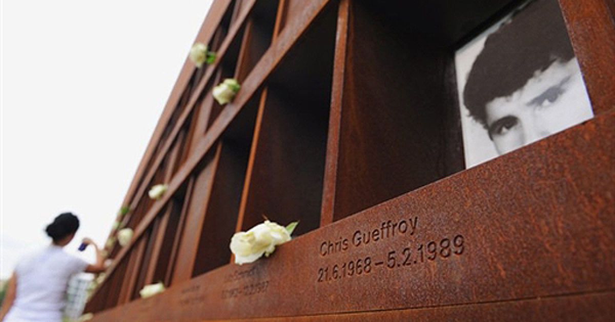Жінка вшановує пам&#039;ять людей, які були вбиті під час спроби перелізти через Берлінський мур. 13 серпня Німеччина відзначає 49 річницю зведення муру. На фото портрет останньої жертви радянських прикордонників Кріса Гоффроя. / © AFP