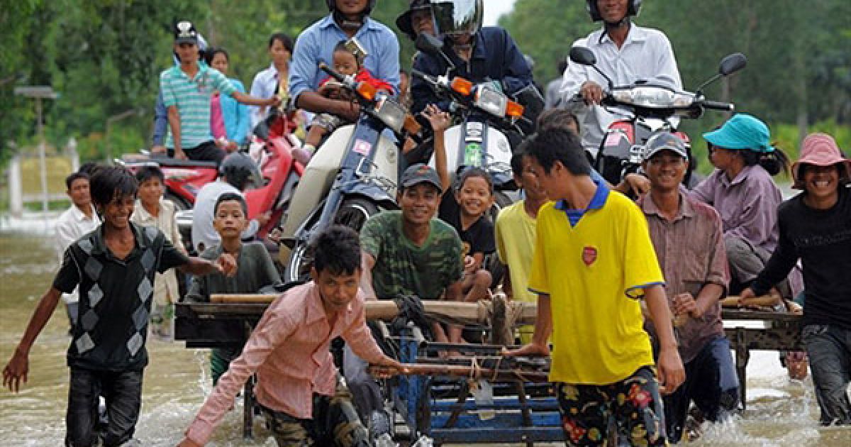 Камбоджа, Такео. Камбоджійські робочі штовхають платформу, завантажену людьми і мотоциклами, через затоплену вулицю у провінції Такео. Сильні повені, від яких потерпають багато провінцій Камбоджі, охопили країну після двох днів сильних дощів. / © AFP
