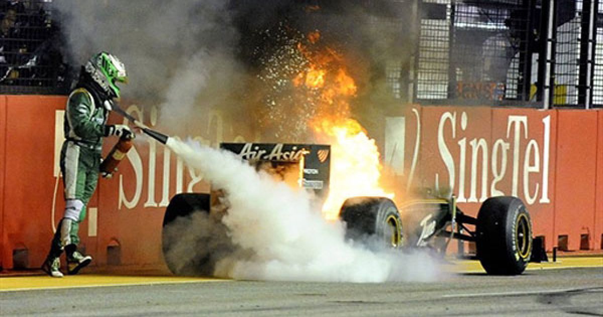 Сінгапур. Фінський гонщик "Формули-1" Хейккі Ковалайнен намагається загасити свій автомобіль, який загорівяс під час сінгапурського гран-прі "Формули-1" у Марина Бей. Гонку виграв іспанець Фернандо Алонсо. / © AFP