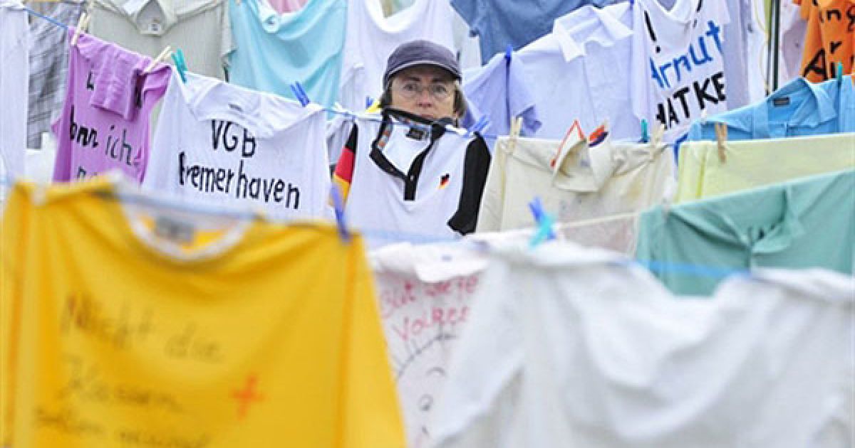 Німеччина, Берлін. Жінка йде повз тисячі футболок, розвішених перед будівлею парламенту у Берліні, під час демонстрації проти планів німецького уряду скоротити витрати на соціальні потреби. Демонстранти зібрали тисячі сорочок, написали на них гасла і закликали уряд збільшити податки для багатіїв. / © AFP