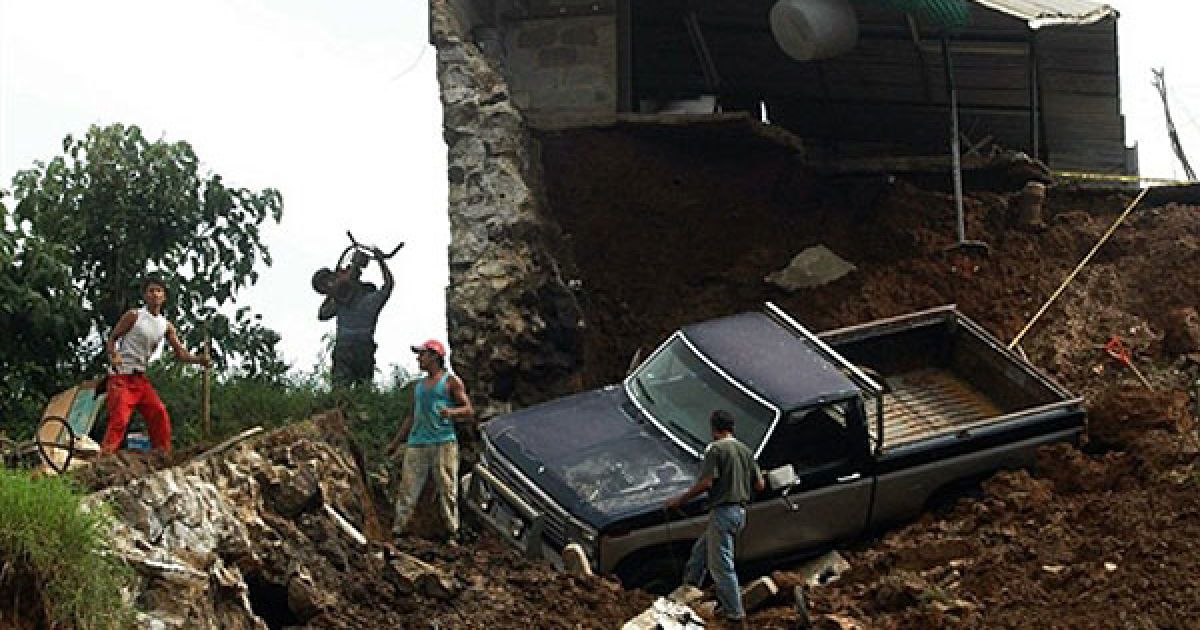 Мексика, Халапа. Люди стоять поруч зі зруйнованим ураганом будинком у місті Халапа, штат Веракрус, Мексика. Ураган Карл обрушився на прибережні райони Мексики, що призвело до екстреної евакуації працівників нафтових вишок, закриття атомної станції. Інший гігантський шторм, Ігор, прямує наразі до Бермудських островів. / © AFP