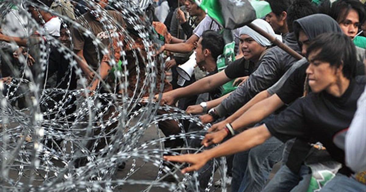 Індонезія, Джакарта. Студенти тягнуть колючий дріт під час антиурядової демонстрації біля президентського палацу у Джакарті. Сотні протестуючих кидали каміння і кийки у поліцейських, які відповіли сльозогінним газом. Акцію влаштували у першу річницю присяги президента Індонезії Сусіло Бамбанга Юдхойоно. / © AFP