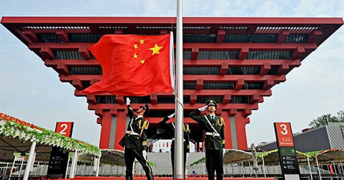 Китай, Шанхай. Китайські солдати урочисто розгортають національний прапор Китаю перед китайським павільйоном на всесвітній виставці "World Expo 2010" у Шанхаї. / © AFP