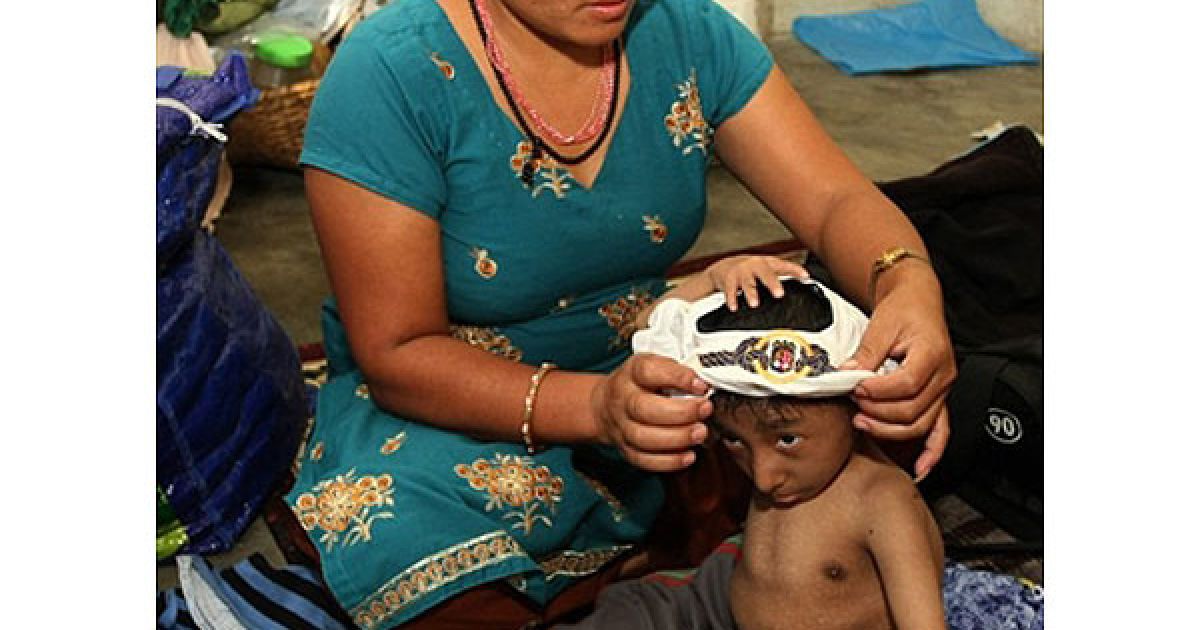 Мати Магара Дхана Майя Тапа допомагає йому вдягнутись / © AFP