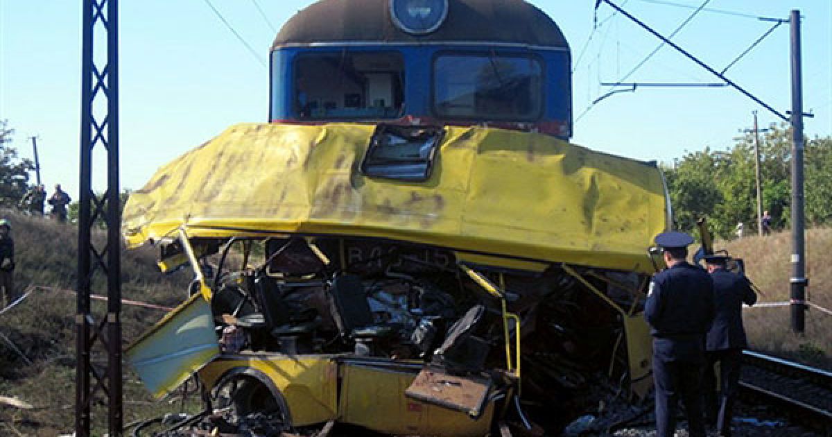 Україна, Марганець. Співробітник міліції стоїть перед автобусом, який врізався у локомотив на переїзді у місті Марганець. Водій пасажирського автобусу "Еталон" виїхав на залізничний переїзд на заборонний сигал у безпосередній близькості до поїзда, що наближався, внаслідок чого й сталася катастрофа. Потяг протягнув автобус на 300 метрів. МНС повідомляє про 41 загиблого, серед яких троє дітей. Ще 10 людей перебувають у лікарнях з тяжкими травмами. / © AFP