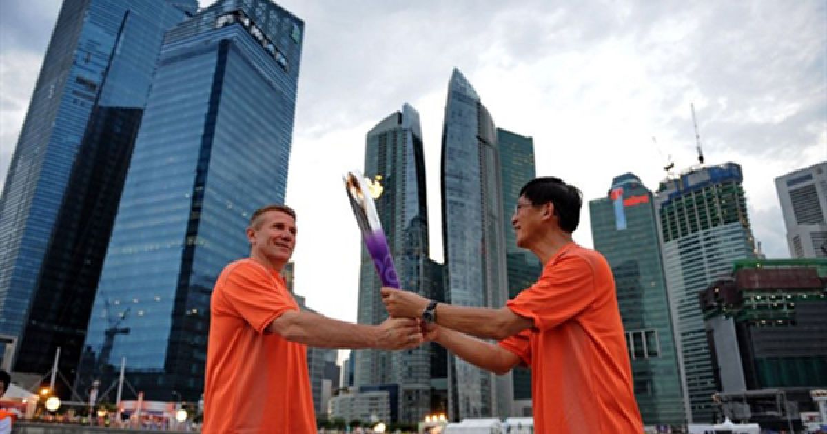 Голова Waterways Watch Society передає Олімпійський вогонь Сергію Бубці у центрі Сінгапура, де завтра відкриються перші Молодіжні Олімпійські Ігри. Молодіжні Олімпійські Ігри були засновані для пропаганди здорового стилю життя серед молоді. / © AFP