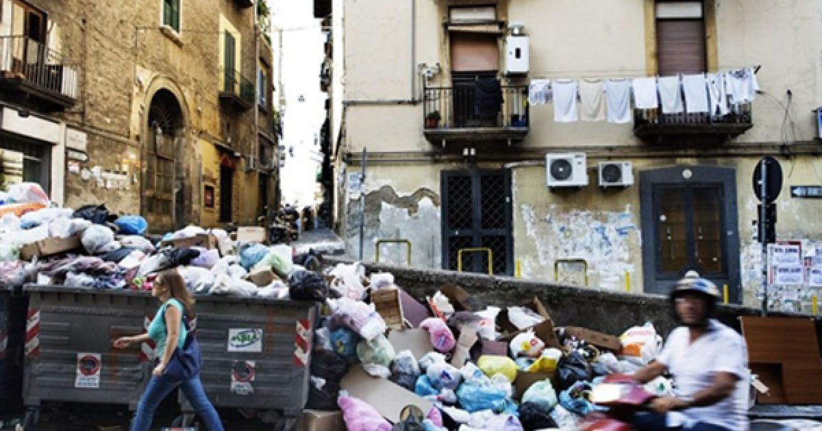 Люди проходять повз сміття на вулицях Неаполі. Учора акція протесту проти будівництва сміттєзвалища на схилах Везувію закінчилися сутичкою демонстрантів із поліцією та підпалом двох сміттєвозів. / © AFP