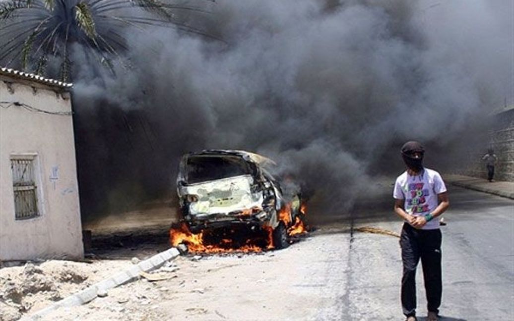 Ємен, Аден. Демонстрант проходить повз палаючий автомобіль під час акції протесту, яка паралізувала південне місто Аден. Протестуючі вимагали від президента країни Алі Абдалли Салеха піти у відставку. / © AFP