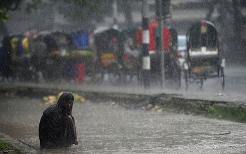 Бангладеш, Дакка. Безпритульний сидить на вулиці, затопленій в результаті сильних опадів у Дацці. Сезонні дощі принесли облегшення жителям столиці Бангладеш, які потерпали від спеки. / © AFP