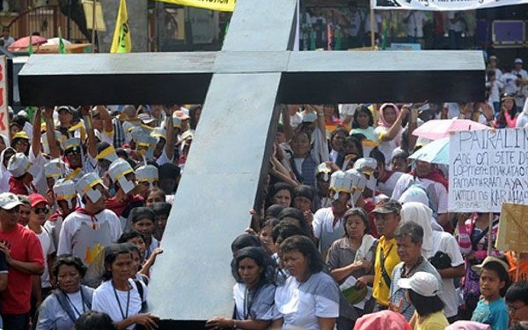 Філіппіни, Маніла. Жінки несуть дерев&#039;яний кількаметровий хрест до Мендіоли у Манілі під час реконструкцій смерті Ісуса Христа. / © AFP
