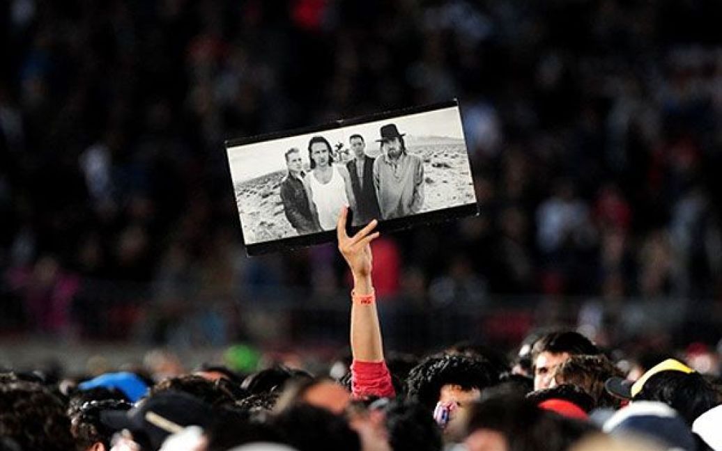 Чилі, Сантьяго. Фанат ірландського гурту U2 тримає фотографію гурту перед концертом U2 на стадіоні Насіональ у Сантьяго. / © AFP