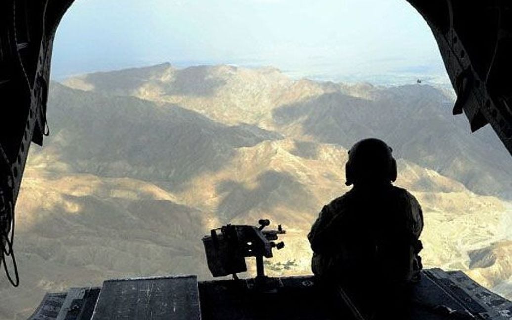 Афганістан. Американський військовослужбовець сидить у задній частині вертольота Chinook, доки вони пролітають повз гори на сході Афганістану. Процес передачі контролю над безпекою країни від іноземних сил афганським військовим почнеться в кінці липня. / © AFP