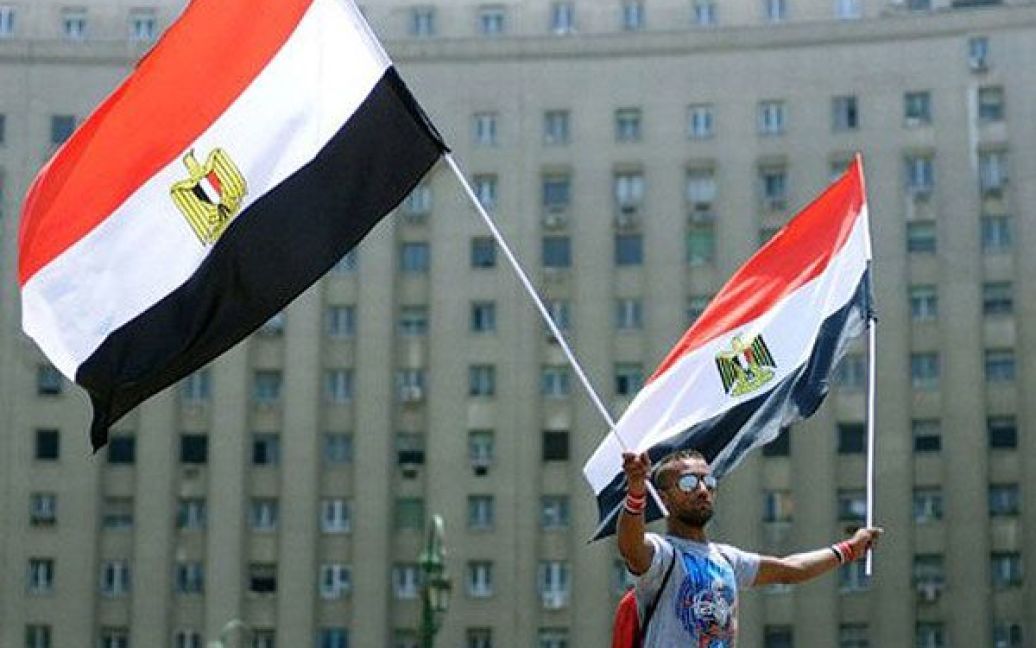 Єгипет, Каїр. Єгиптянин розмахує національними прапорами під час акції протесту на площі Тахрір в Каїрі, де почалась сидяча акція протесту проти дій єгипетського прем&#039;єр-міністра. / © AFP