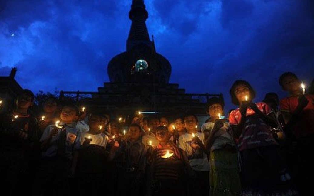 Індія, Сілігурі. Індійські школярі з Гімалайської буддійської культурної школи разом з тибетськими ченцями моляться при свічках за духовного лідера Тибету Далай-ламу під час його святкування його 76-го дня народження в місті Сілігурі. / © AFP