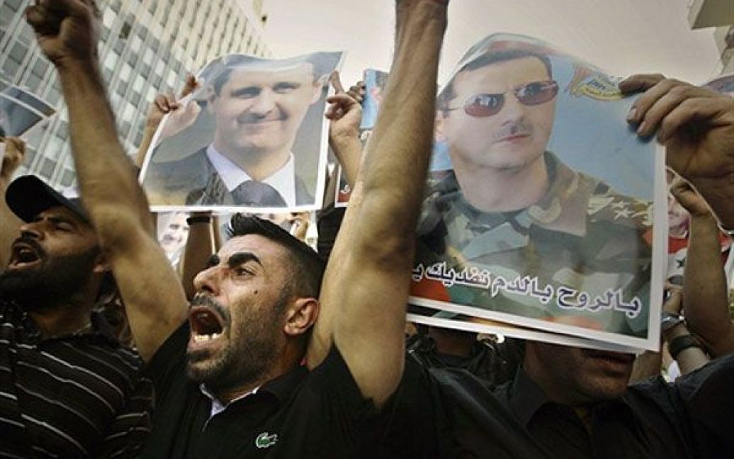 Ліван, Бейрут. Сирійські чоловіки тримають фотографії президента Сирії Башара Аль-Асада під час демонстрації на його підтримку під час акції в Бейруті. / © AFP