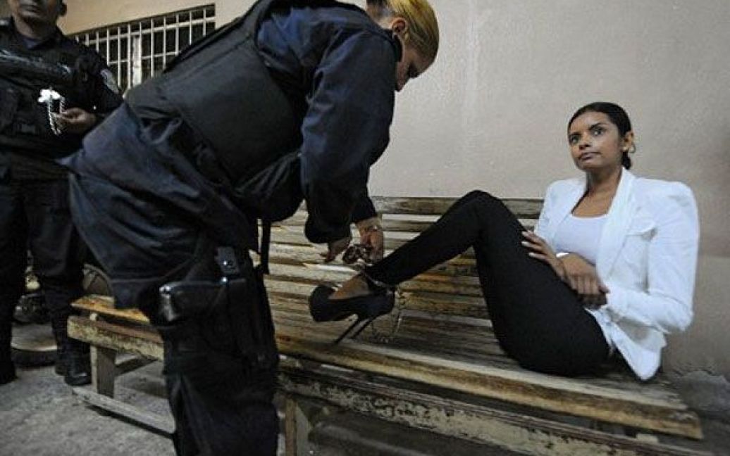 Гондурас, Тегусігальпа. Поліцейський знімає кайдани з ніг колишньої Міс Гондурас Бельгіки Наталії Суарес в залі суду у Тегусігальпі. Колишню королеву краси, громадянку Нікарагуа, затримали з 33 тисячами євро і звинувачують у відмиванні грошей. / © AFP