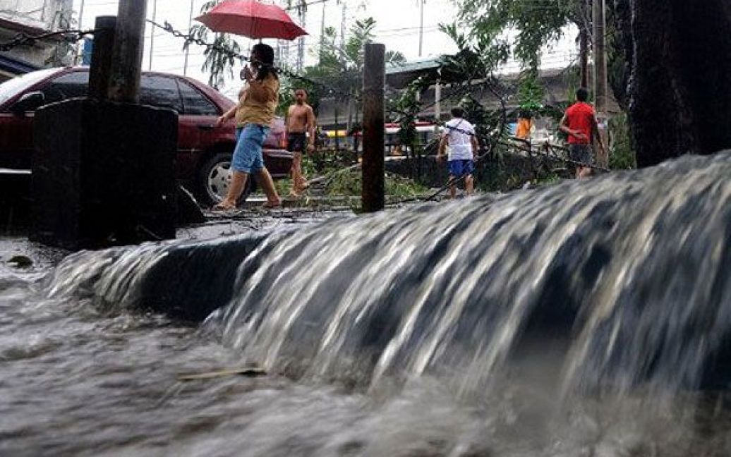 Філіппіни, Маніла. Люди проходять повз вулиці, затоплені під час тривалих проливних дощів, викликаних тропічним штормом Meari. Майже 50 тисяч осіб були переміщені до евакуаційних центрів на Філіппінах. / © AFP