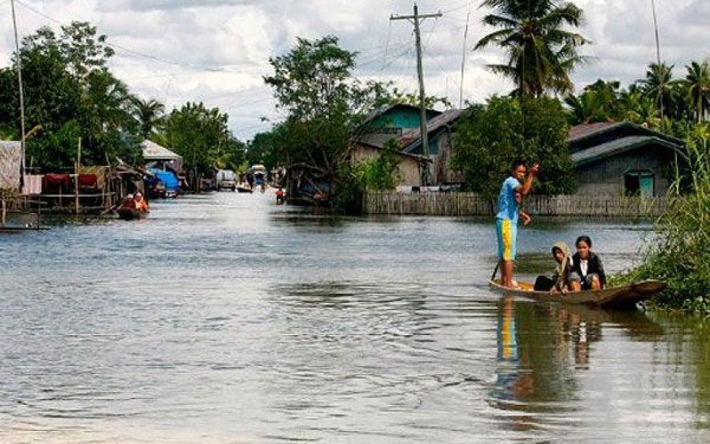 Філіппіни, Магінданао. Місцеві мешканці на човні пересуваються затопленими вулицями міста Магінданао. Принаймні, чотири людини загинули в результаті сильної повені на Філіппінах. / © AFP