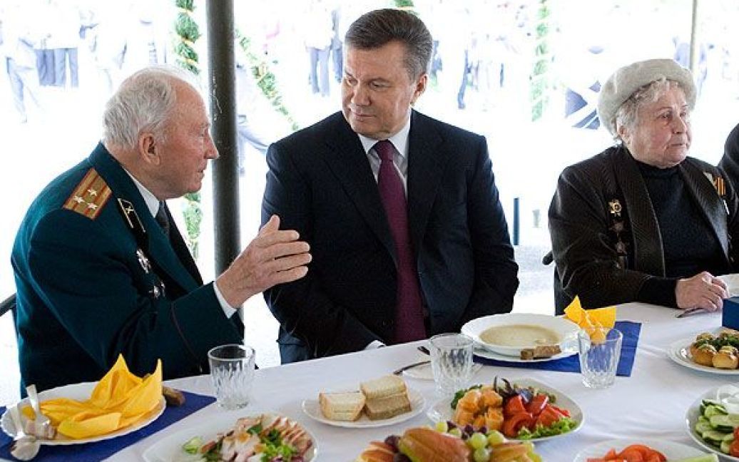 Віктор Янукович разом із ветеранами посидів за святковим столом, але у меню солдатської каші не було, натомість - банани, ковбаска, огірки та помідори і фронтові сто грам. / © President.gov.ua
