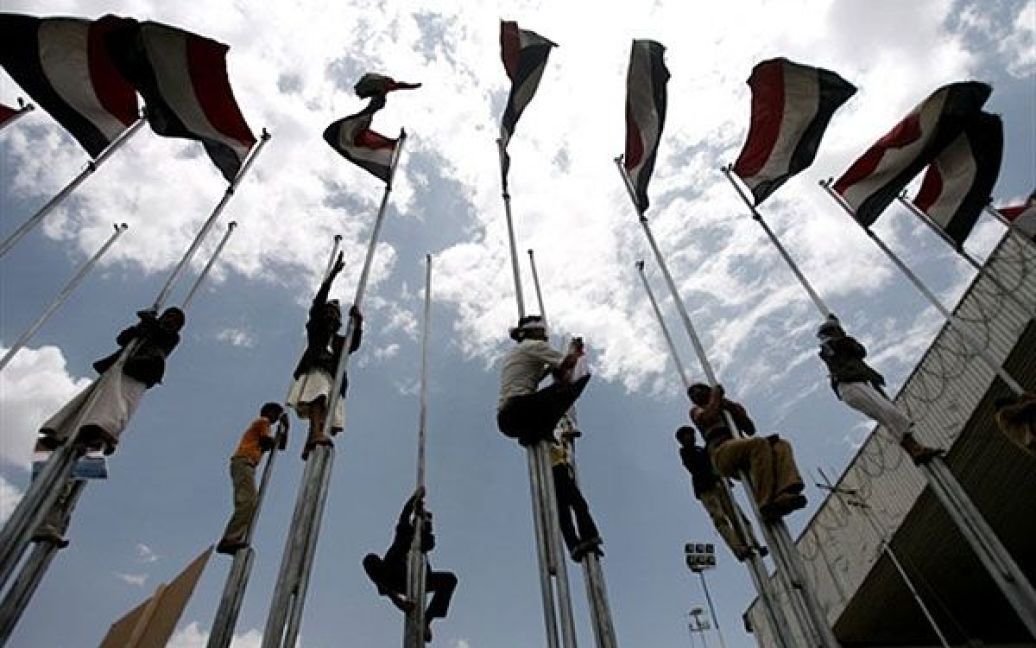 Ємен, Сана. Прихильники президента Ємену Алі Абдуллі Салеха піднімаються на флагштоки під час провладного мітингу в Сані. / © AFP