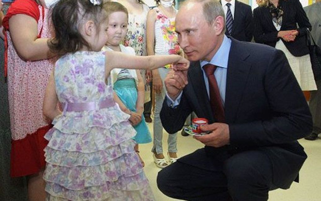 Росія, Москва. Прем&#039;єр-міністр Росії Володимир Путін цілує руку дівчини під час відвідування відкриття нового дитячого медичного центру в Москві. / © AFP