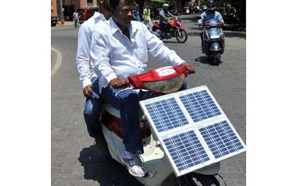 Індія, Мумбаї. Аюб Хан Патан та його племінник Імран катаються на саморобному електричному скутері, який вони збирали зі старих скутерів протягом трьох років. Екологічно чистий транспортний засіб, який працює на сонячній енергії, коштуватиме 415 євро і зможе проїхати близько 60 км з одного повного заряду. / © AFP