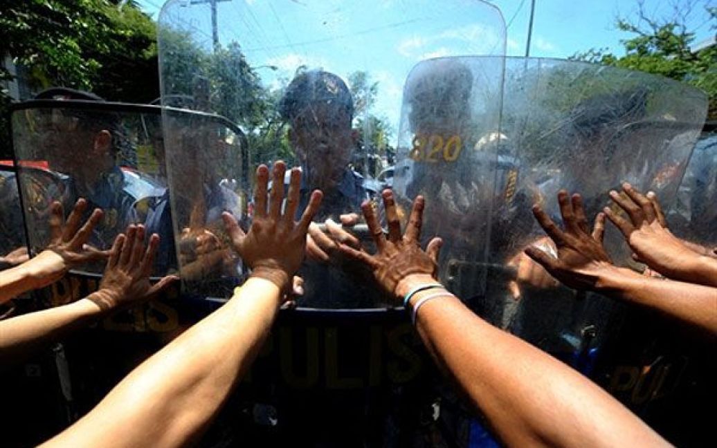 Філіппіни, Маніла. Протестуючі штовхають поліцейські щити під час мітингу перед палацом в Манілі. Акцію провели проти відмови уряду збільшити мінімальну заробітну плату. / © AFP