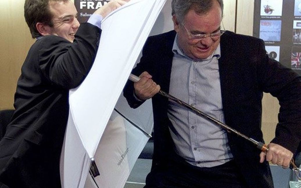 Франція, Парижю. Французький голова компанії "Щирий Шербур" Жан-П&#039;єр Івон захищається парасолькою від свого сина в Парижі під час ярмарку "Зроблено у Франції". / © AFP