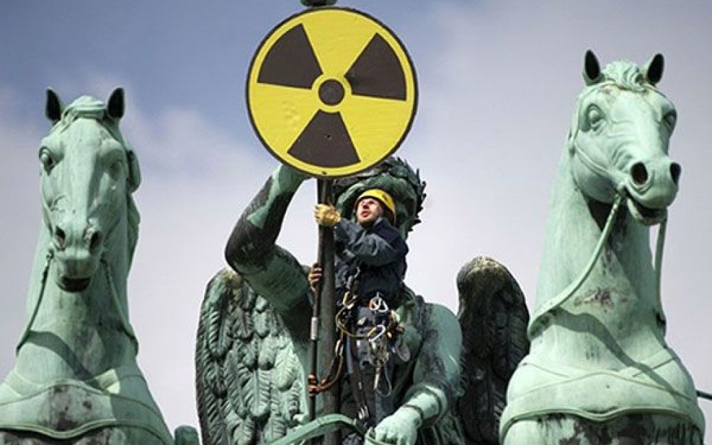 Німеччина, Берлін. Активіст руху "Грінпіс" встановлює знак боротьби з ядерною загрозою на квадризі Бранденбурзьких воріт у Берліні. Група антиядерних протестувальників встановила у Берліні плакати з написом "Кожен день з атомною енергетикою &mdash; це вже занадто". / © AFP
